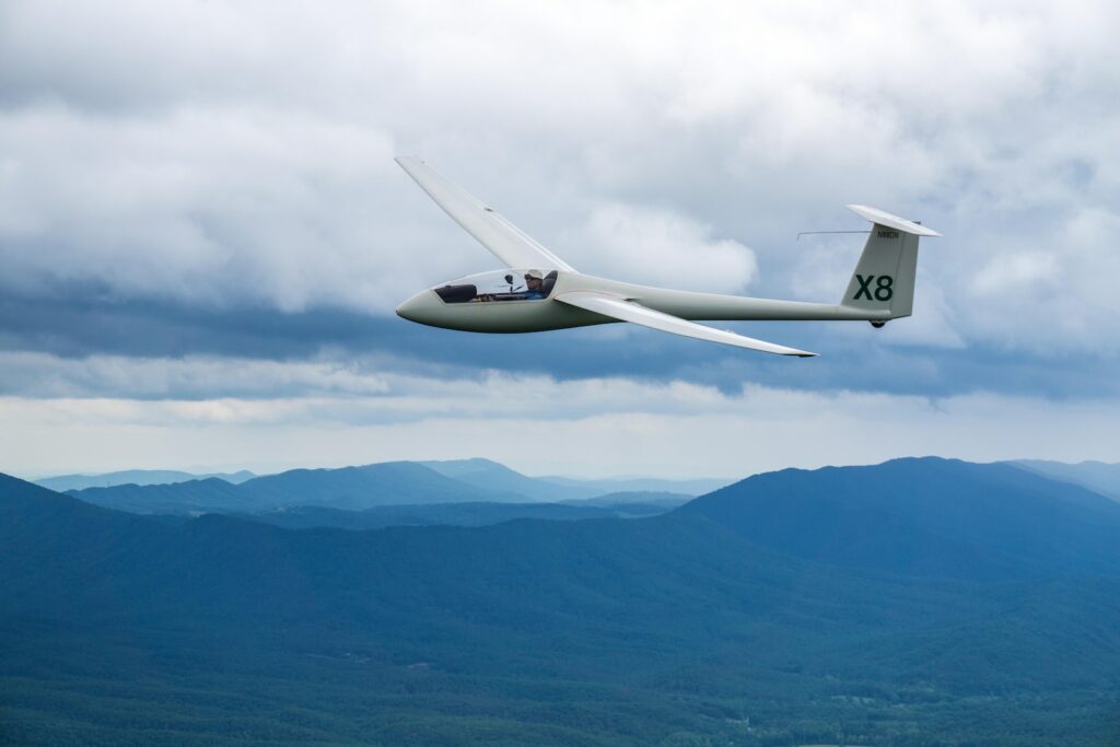 white X8 plane above mountains during daytime