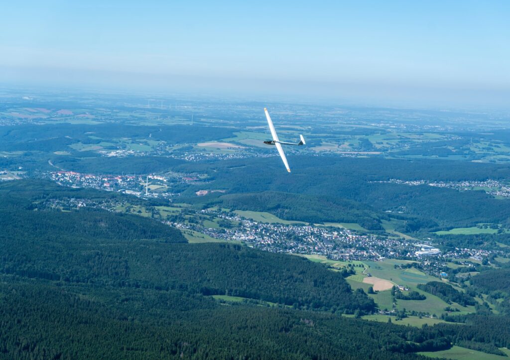 white airplane flying over green grass field during daytime